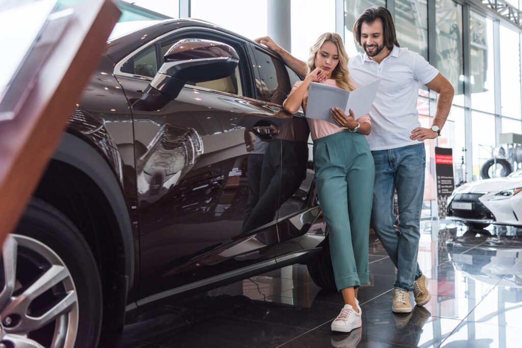 couple with catalog buying car at dealership salon