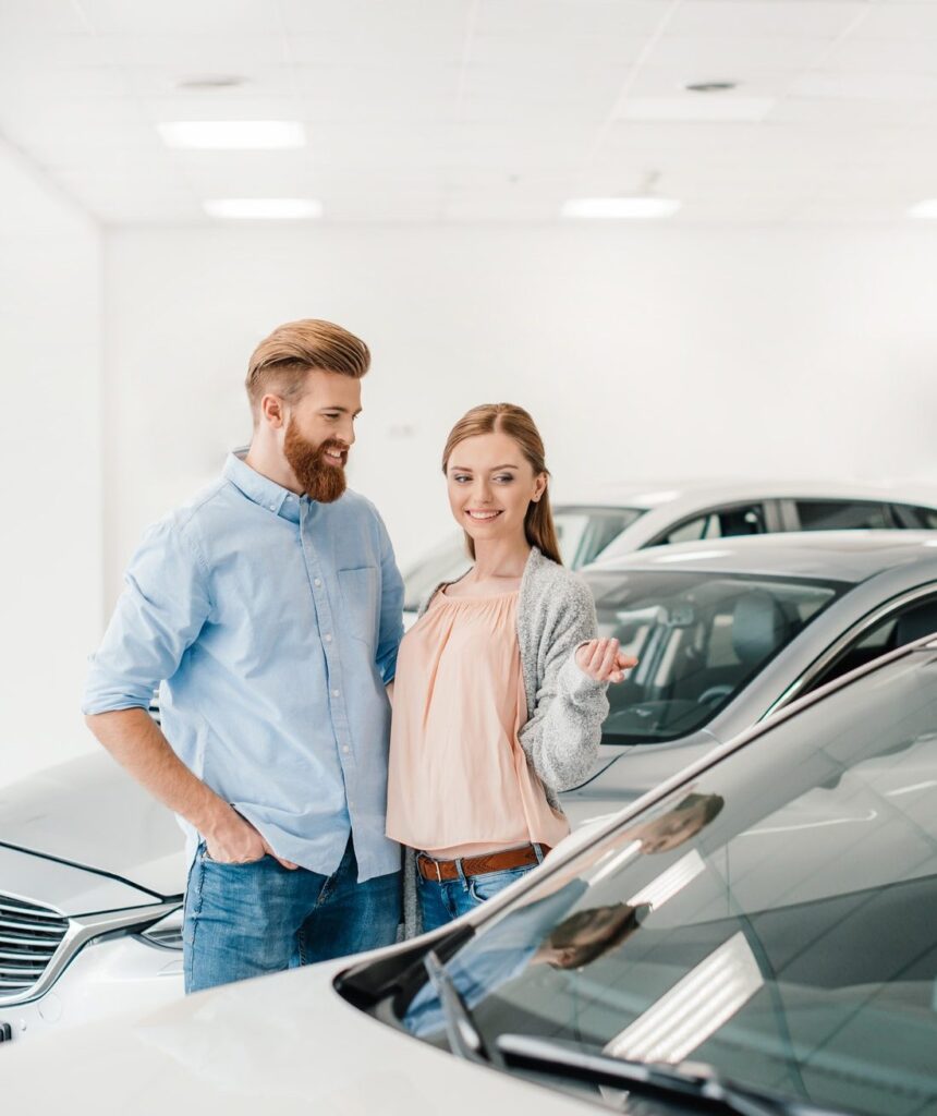 الرئيسية 13 happy couple choosing car in dealership salon woman pointing on car e1616394658847