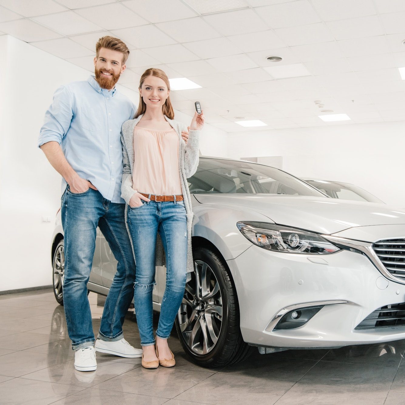 الرئيسية 9 happy couple with car key standing at car in dealership salon e1616384906835